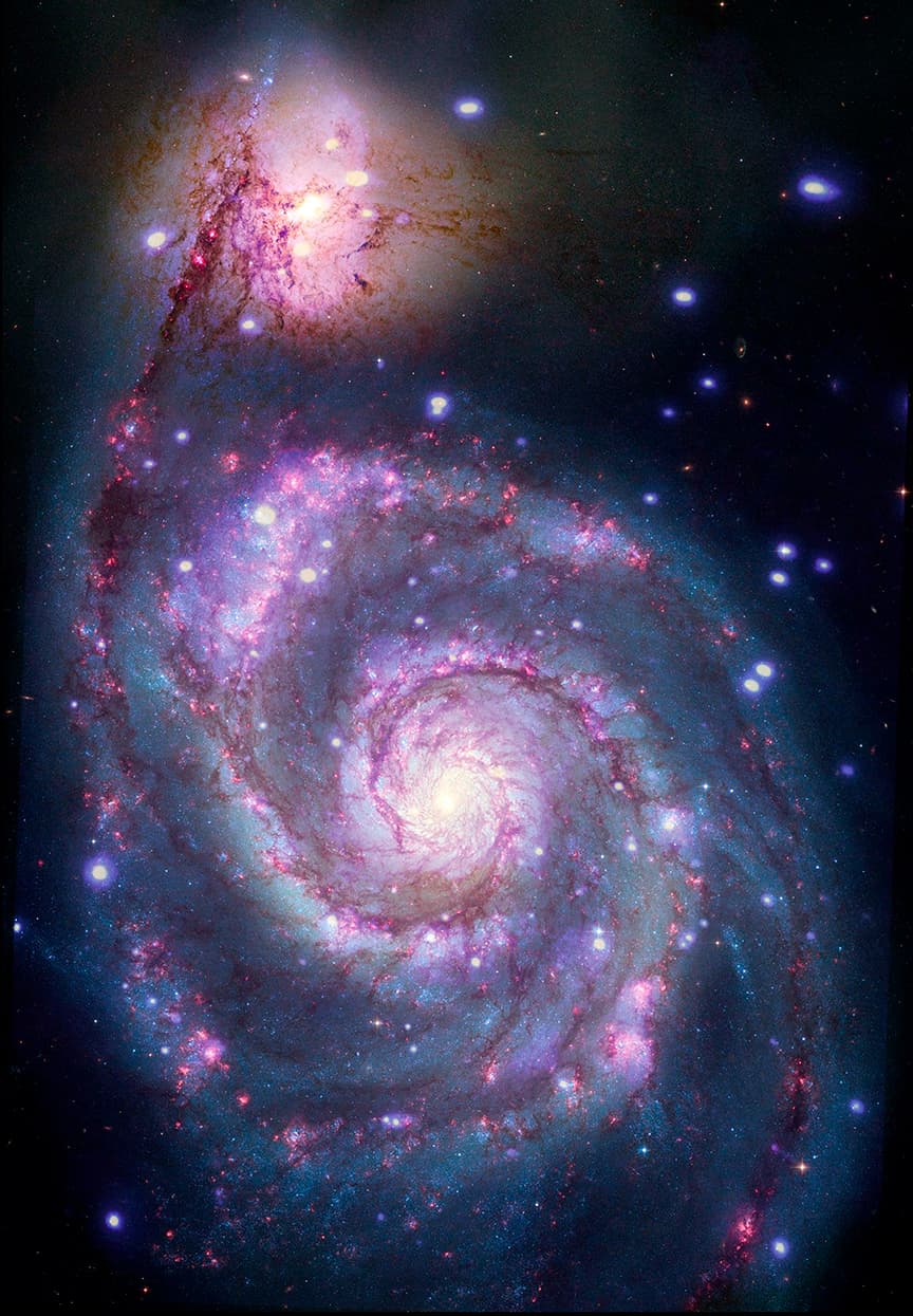 The composite image includes data from both X-ray and Optical light. It features the entirety of the M51 galaxy, which indeed resembles a swirling whirlpool in a black sea, viewed from above. At the core of the cloudy blue whirlpool is a bright white light from which wispy spiraling arms appear to swirl. The swirling arms are the color of red wine and resemble long tendrils of smoke. Along the lengths of the spiraling arms are specks of light in white and neon purple. One of the spiraling arms curves up toward our upper left. There, it appears to dissipate in a pool of pale purple light. Overlaid on one of the spiraling arms, to our right of the bright white core, is a box rendered in thin white lines. Inside this box is a speck of white light. Here, astronomers have detected the first evidence of a possible planet passing in front of a star outside of our Milky Way. In this small spot in the M51 galaxy, Astronomers and researchers have detected a dimming of X-rays from a system where a large star is in orbit around a small, dense neutron star or black hole. The dimming is interpreted as being a planet passing in front of the bright, dense object. For this release, that interpretation has been illustrated by an artist.